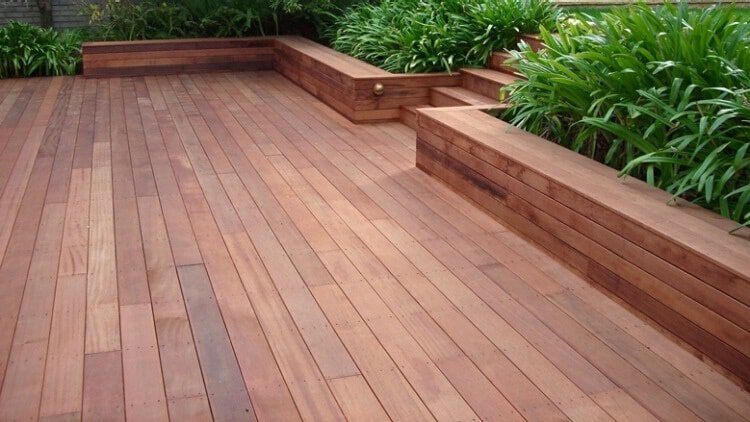 Wooden deck with built-in steps, surrounded by lush greenery.