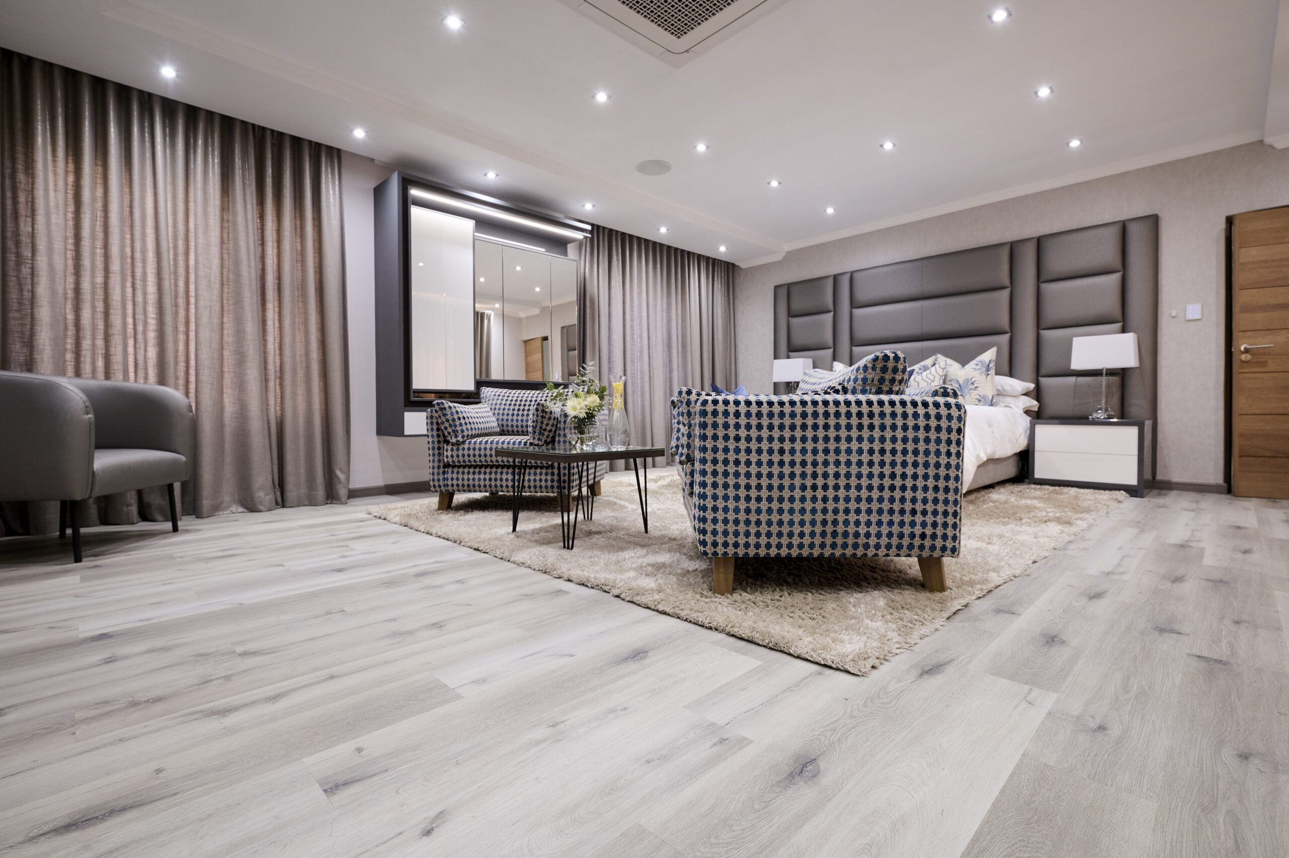 Modern bedroom with light wooden flooring, checkered chairs, and cozy lighting.
