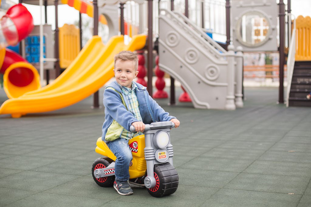 A young boy rides a toy motorbike in an outdoor playground, having fun and playing.