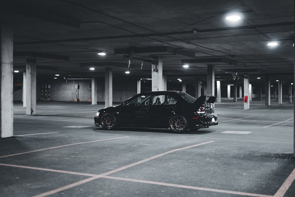 Black Mitsubishi Lancer Evolution parked in a dimly lit urban parking garage.
