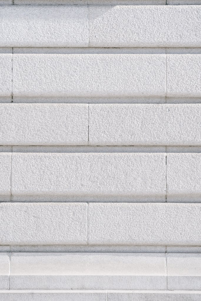 Full frame textured background of white wall with rows of bricks at daylight