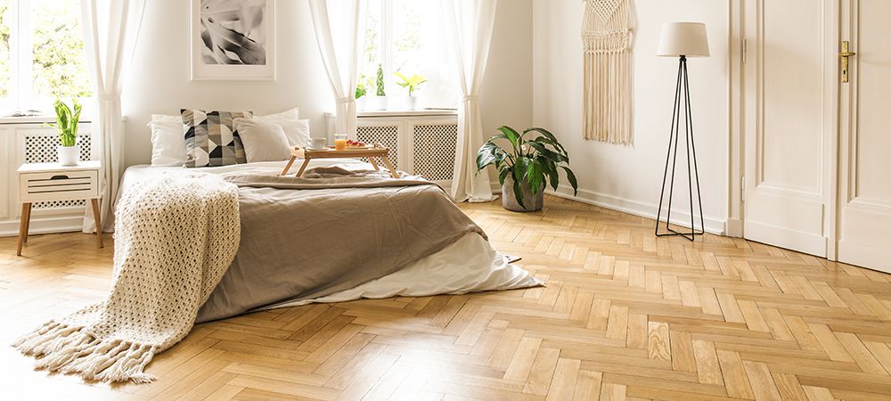 Living room with light herringbone wood flooring, a gray sofa, and wooden furniture.