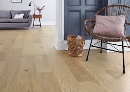 Living room with light wooden flooring, a cozy armchair, and a modern gray sofa, with a stylish woven basket in the corner.