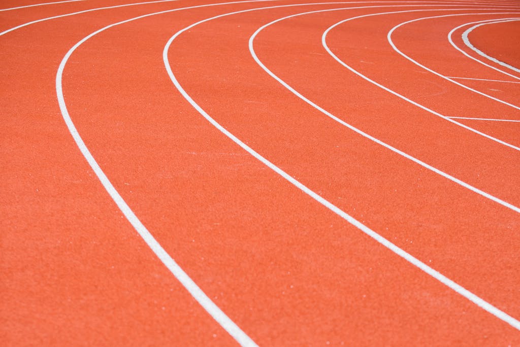 Red running track with distinct white lane markings and rubberized surface.