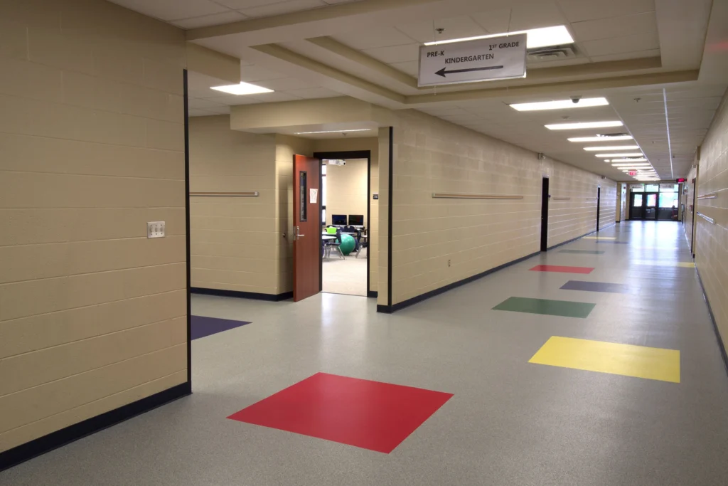 School hallway with brightly colored floor tiles and classroom doorways.