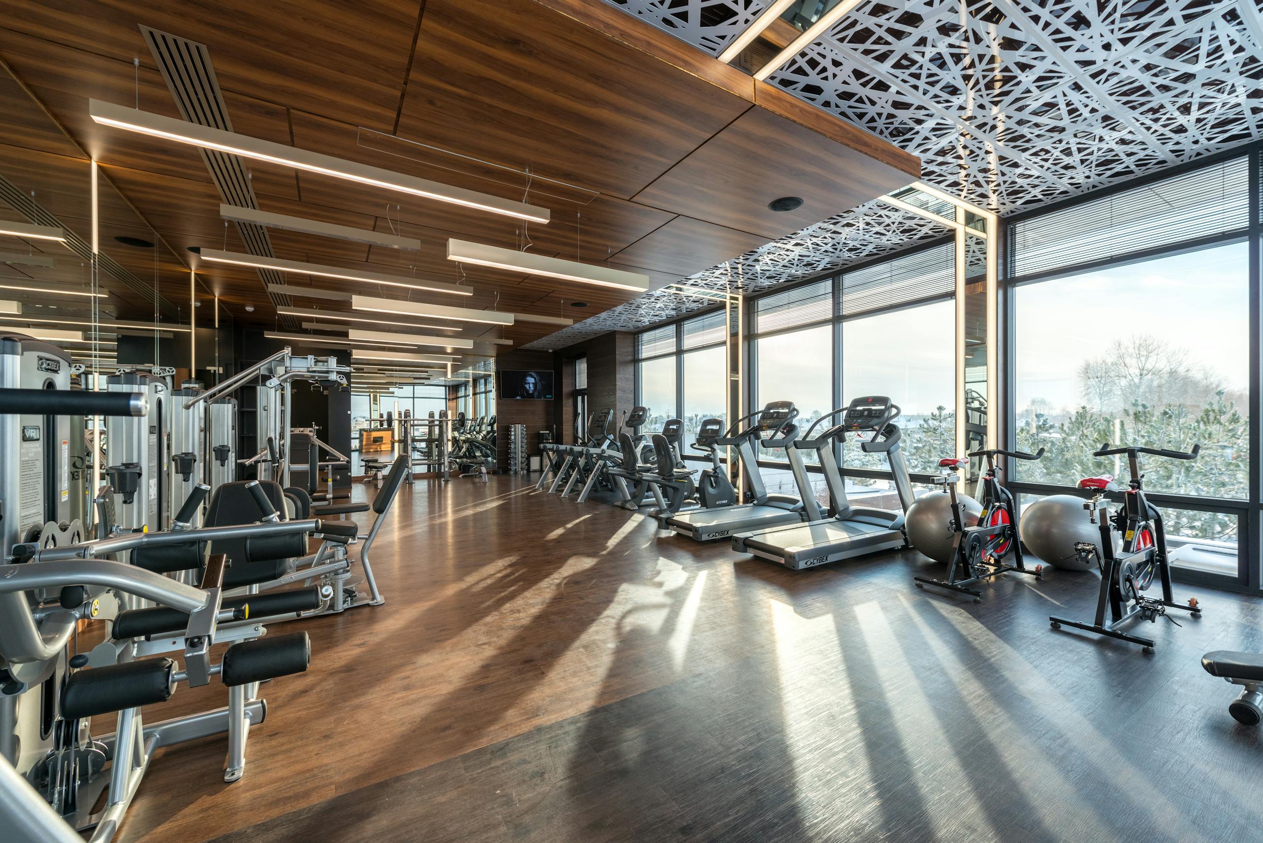 Spacious modern gym with treadmills, exercise bikes, and weights under natural lighting.
