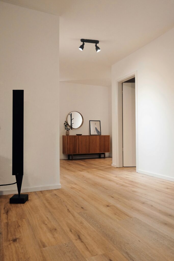 Hallway featuring light wooden flooring, a wooden console table, and minimalist décor, highlighted by modern lighting.