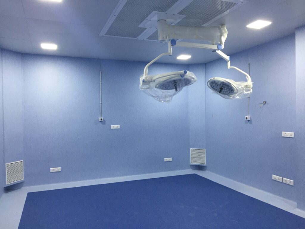 Clean blue vinyl flooring in a modern hospital operation theatre with ceiling-mounted surgical lights.