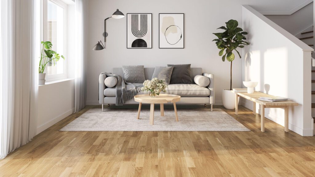 Living room with light hardwood flooring, a gray sofa, modern artwork, and plants.
