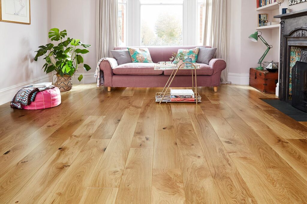 Living room with light oak wood flooring, a pink sofa, a coffee table, and plants.